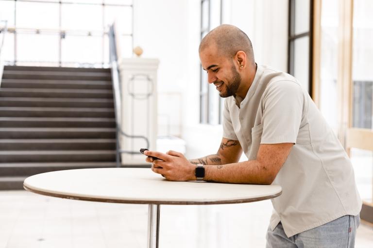 male leans on table reading a phone