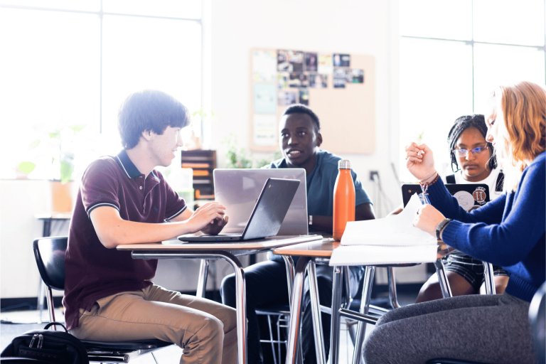 Students sitting in a physical classroom, looking at Canvas LMS